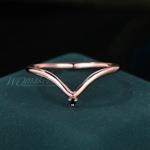 May include: A rose gold V-shaped ring with a small black gemstone in the center.