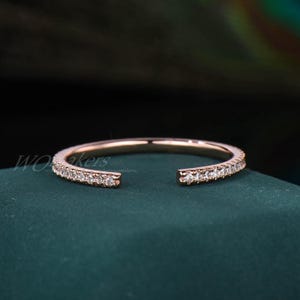 May include: A rose gold band ring with a single row of small clear diamonds.