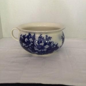 May include: A white ceramic chamber pot with a blue and white floral design.