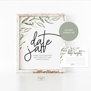 Peut inclure: Une affiche imprimable avec des feuilles vertes et le texte "date jar" et des instructions pour partager une idée de rendez-vous préférée avec le couple heureux. L'affiche est encadrée dans un cadre en bois blanc. Une petite carte avec le texte "date night" est également incluse.