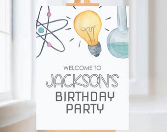 Może przedstawiać: Białe powitalne tabliczka z ilustracją żarówki, atomu i zlewki. Tabliczka głosi "Witamy na przyjęciu urodzinowym Jacksona".