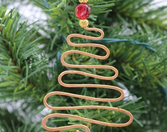 May include: A copper wire Christmas tree ornament with a red and gold bead at the top.