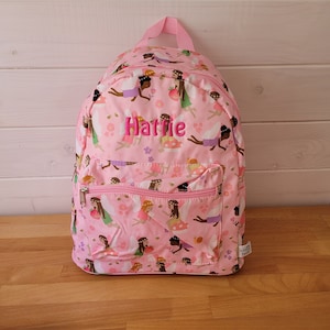 May include: Pink backpack with a fairy pattern and the name "Hattie" embroidered on the front. The backpack has a zippered pocket on the front and a small tag on the bottom right corner.