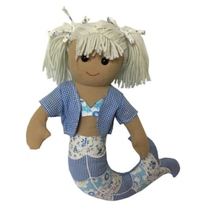 Puede incluir: Muñeca de trapo hecha a mano con forma de sirena. La muñeca tiene pelo de hilo rubio claro, una cara bronceada y lleva una chaqueta de cuadros azul y un top de bikini floral. La cola de sirena es de retazos azules y blancos.