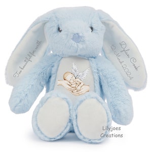 Könnte beinhalten: Ein hellblauer Plüschhase mit gesticktem Text, der auf einem Ohr "Too beautiful for earth" und auf dem anderen Ohr "Dylan Cook 12 March 2024" lautet. Der Hase hat einen weißen Fleck auf der Brust mit einer Illustration eines Babyengels mit Flügeln. Die Füße des Hasen sind weiß. Der Text "Lilyjoes Creations" ist auf der Unterseite eines Fußes gestickt.
