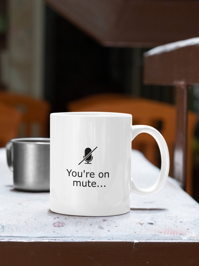 May include: White ceramic mug with a black microphone icon with a line through it and the text "You're on mute..." printed on the front.