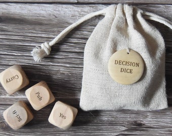 May include: A set of wooden dice with different words on each side, including "Curry", "Pub", "Yes", and "Selfie". The dice are in a small white drawstring bag with a round tag that says "Decision Dice".