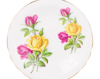 May include: White plate with a scalloped edge and a gold rim. It features a floral design of yellow and pink roses with green leaves. The roses are arranged in two clusters on the plate.