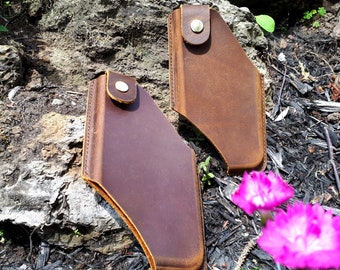 May include: Two brown leather phone cases with a stitched edge and a gold button closure.