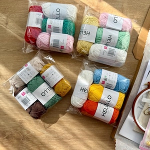 May include: Several packs of colourful yarn in clear plastic wrapping. The yarn shades include red, white, green, pink, yellow, brown, orange, and blue. Each pack is labelled with the word "HELLO".