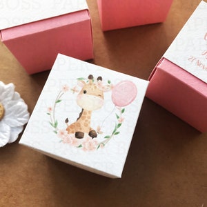Peut inclure: Une bo&icirc;te &agrave; drag&eacute;es blanche avec un couvercle rose. La bo&icirc;te est illustr&eacute;e d'une aquarelle repr&eacute;sentant une girafe avec un ballon rose. Le texte sur la bo&icirc;te est "Camila Isabel 27 Noviembre 2021".