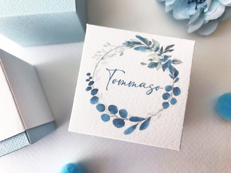 May include: A white gift box with a blue watercolor wreath and the name "Tommaso" written in blue cursive.