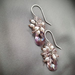 May include: A pair of silver dangle earrings with a cluster of pink and white beads and a teardrop-shaped crystal.