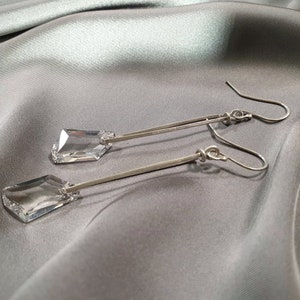 May include: A pair of silver dangle earrings with clear crystal teardrop-shaped stones.