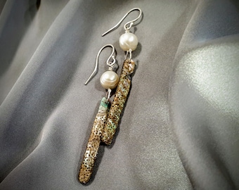 May include: A pair of silver dangle earrings with a white pearl and a brown and green textured pendant.