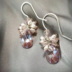 May include: A pair of dangle earrings with a teardrop-shaped crystal and a cluster of pink and white beads.