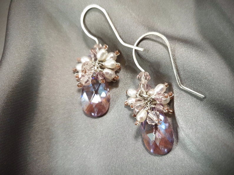 May include: A pair of dangle earrings with a teardrop-shaped crystal and a cluster of pink and white beads.