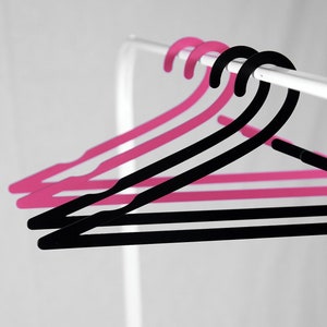 May include: Three hangers, two pink and one black, hang on a white rod.