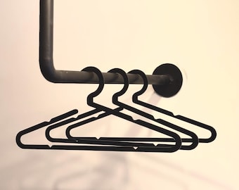 May include: Four black plastic hangers hanging on a black metal rod.