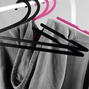 May include: A gray hooded sweatshirt hanging on two black and two pink plastic hangers.