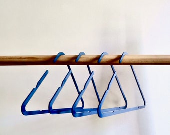 Könnte beinhalten: Fünf blaue Plastikbügel hängen an einer Holzstange.