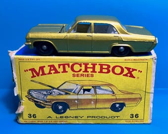 May include: A gold Matchbox Series 36 die-cast toy car model of an Opel Kadett. The car is in its original box, which has the Matchbox logo and the words "A Lesney Product" printed on it.