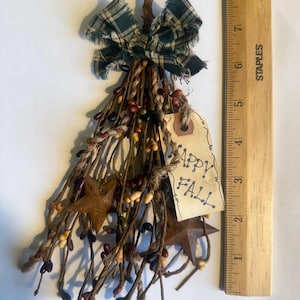 May include: A rustic fall decoration featuring a bundle of twig-like stems adorned with colorful berries and star-shaped accents. A plaid bow and a tag that reads "Happy Fall" complete the design. The decoration measures approximately 8 inches in length.