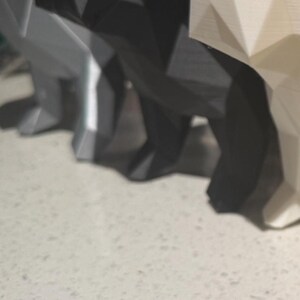 May include: Four geometrically shaped dog figurines, each with a different color. The figurines are made of a smooth, glossy material. The colors are black, white, gray, and gold.