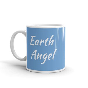 May include: A white ceramic mug with a light blue background and the text "Earth Angel" in white cursive font.
