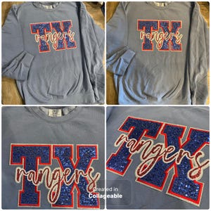 May include: Light blue sweatshirt with the text "TX rangers" in a sequined design. The letters "TX" are in blue sequins with a red outline, and "rangers" is in a cursive font with white and red accents. The sweatshirt has ribbed cuffs.