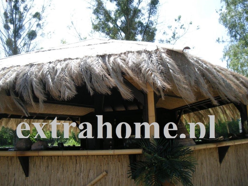 K&ouml;nnte beinhalten: Ein Geb&auml;ude mit Strohdach und Bambusz&auml;unen, mit dem Text "extrahome.nl". Das Dach besteht aus getrockneten Palmbl&auml;ttern, und die Struktur scheint eine Bar oder ein Sitzbereich im Freien zu sein. Die Gesamt&auml;sthetik ist tropisch.
