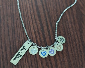 May include: A silver necklace with a charm that says "I love you" and several heart-shaped charms with different colored outlines.