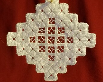Op de afbeelding: Witte gehaakte sneeuwvlok ornament met een gouden lint om op te hangen.