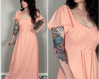 May include: A peach-coloured maxi dress with a scoop neck and short, flared sleeves. The dress has a fitted bodice and a flowing skirt.