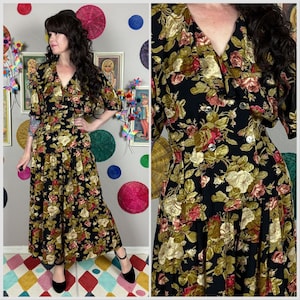 Puede incluir: Vestido vintage negro con estampado floral de rosas rojas, doradas y verdes. El vestido tiene cuello en V, mangas cortas y botones en la parte delantera. La falda es de largo midi.