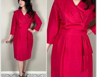 May include: A vibrant pink dress with a large, folded collar and a fitted silhouette. The dress has a v-neckline and three-quarter sleeves.