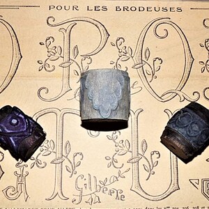 May include: Three vintage wooden printing blocks with intricate designs. The blocks are carved with floral patterns and are in shades of blue and purple.
