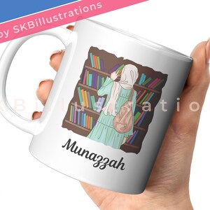 May include: White ceramic mug with a colorful illustration of a person in a hijab standing in a library, reading a book. The text "Munazzah" is printed on the mug.