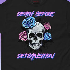 May include: Black t-shirt featuring a skull graphic with blue and pink roses. The text "DEATH BEFORE DETRANSITION" is displayed above and below the skull in a gradient font.
