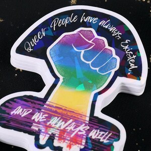 Queer People have always existed, and always will, Broken Glass Style Holographic 3 inch sticker, rainbow colored power fist on black background