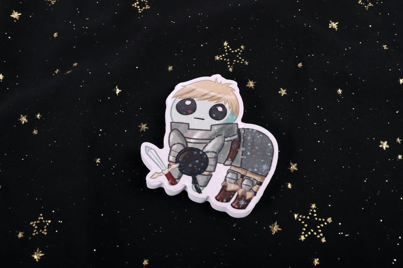 A holographic sticker Of Laios Touden  of Dungeon Meshi / Delicious in dungeon imagined as the yippee / Autism Creature. The sticker is on a black background with gold glitter.