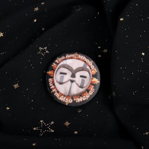 A squishy plush pin of Esquie from Expedition 33- It features Esquie's head from Clair Obscur Expedition 33 featuring the text: "I am too "Whooo" but I am also "Wheee"