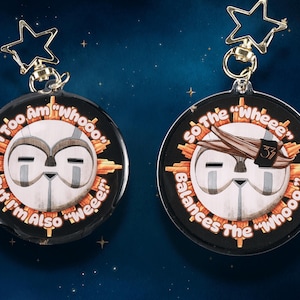 Puede incluir: Dos llaveros redondos con caras de búho de dibujos animados. Uno tiene el texto "I Too Am 'Whooo' But I'm Also 'Weee'!" El otro dice "So The 'Wheee' Balances The 'Whooo'!" Ambos tienen cierres dorados en forma de estrella.