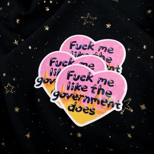 A flaming heart-shaped sticker with the text "Fuck me like the government does"