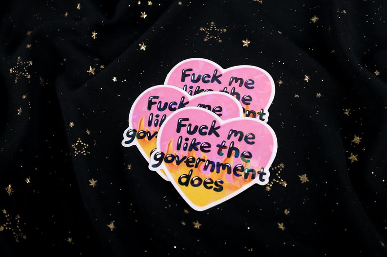 A flaming heart-shaped sticker with the text "Fuck me like the government does"