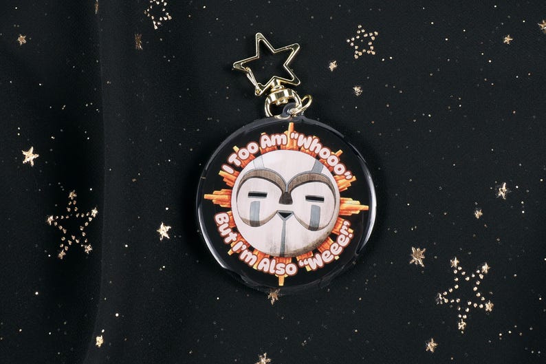 The Front of the Esquie Keychain. It features Esquie's head from Clair Obscur Expedition 33 featuring the text: "I am too "Whooo" but I am also "Wheee"