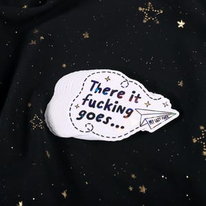 A sticker with the phrase "There it fucking goes..." and a small paper airplane graphic flying away that says "My Last Fuck"