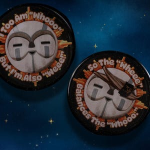 May include: Two black round buttons with a cartoon owl design. One button reads "I Too Am 'Whooo' But I'm Also 'Weee!'" The other says "So The 'Wheee' Balances The 'Whooo'." The background is a starry night.