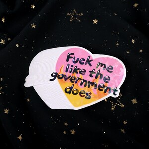 A flaming heart-shaped sticker with the text "Fuck me like the government does"