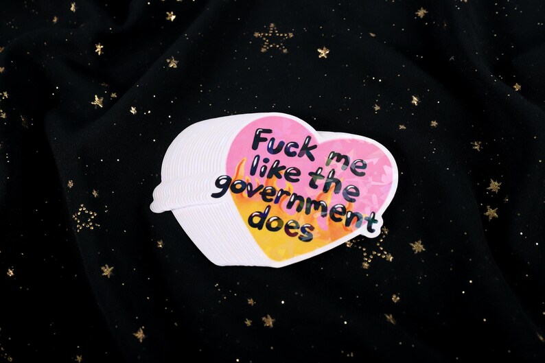 A flaming heart-shaped sticker with the text "Fuck me like the government does"